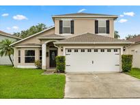 Charming two-story home with a well-manicured lawn and a two-car garage, enhanced by black shutters at 114 Harwood Cir, Kissimmee, FL 34744