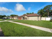 Charming single-story home with a two-car garage, lush lawn and well-maintained landscaping at 12542 Idaho Woods Ln, Orlando, FL 32824