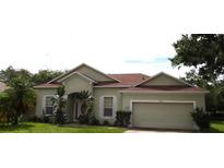 Inviting single-story home featuring a well-maintained lawn, attached two-car garage, and classic architecture at 3074 Bay Laurel N Cir, Kissimmee, FL 34744