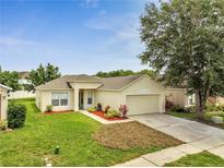 Well-maintained single-Gathering home featuring a two-car garage and a nicely landscaped front yard at 3274 Hunters Chase Loop, Kissimmee, FL 34743