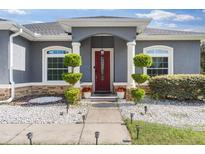 Charming front entrance with a red door, manicured bushes, and stone detailing at 3292 Sw 133Rd Lane Rd, Ocala, FL 34473