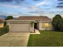 Charming single-story home featuring a manicured lawn, a two-car garage, and an inviting front entrance at 440 Peppermill Cir, Kissimmee, FL 34758