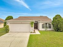 Charming single-story home featuring a two-car garage, well-manicured lawn, and inviting front entrance at 440 Peppermill Cir, Kissimmee, FL 34758