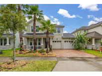 Inviting two-story home featuring a three-car garage, front porch, and lush landscaping with palm trees at 4952 Creekside Park Ave, Orlando, FL 32811