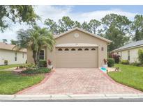 Charming single-story home featuring a brick driveway, lush landscaping, and a welcoming front facade at 516 Millifiora Ln, Kissimmee, FL 34759