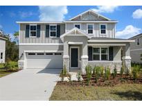 Charming two-story home with a two-car garage, gray siding and lovely landscaping at 555 Summit River Dr, Apopka, FL 32712