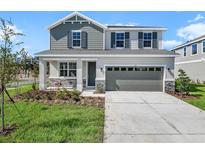 Charming two-story home featuring a two-car garage, stone accents, manicured lawn, and stylish gray and white facade at 660 Summit River Dr, Apopka, FL 32712