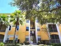 Inviting yellow condo building featuring well-maintained landscaping and a calming atmosphere with mature trees and clear blue skies at 1325 Lake Shadow Cir # 12205, Maitland, FL 32751