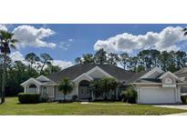 Well-maintained single-Gathering home featuring a manicured lawn, mature trees, and a two-car garage at 2356 Chadwick Cir, Kissimmee, FL 34746