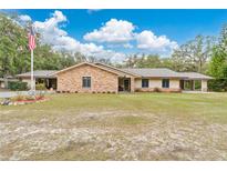 Inviting single-story home features an American flag, a manicured front lawn, and a brick facade accented with tan trim at 4410 Mildred Bass Rd, St Cloud, FL 34772