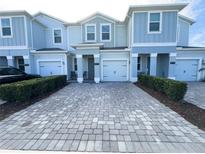 Charming townhome showcasing a paver driveway and manicured landscaping at 4736 Tribute Trl, Kissimmee, FL 34746