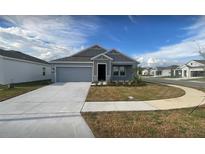 Charming single-story home with a well-manicured lawn, a gray exterior, and a two-car garage at 553 Se Turtle, Haines City, FL 33844