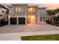 Charming two-story home with a paved driveway, stone accents, balcony, and a two-car garage at 7802 Palmilla Ct, Reunion, FL 34747