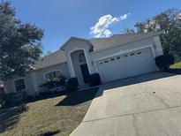 Charming single-story home with manicured lawn and a two-car garage and a front door underneath an archway at 808 Massy Ct, Kissimmee, FL 34759