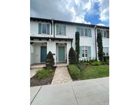 Charming townhome featuring blue shutters and doors, complemented by lush landscaping and a welcoming walkway at 8919 Lakeshore Pointe Dr, Winter Garden, FL 34787