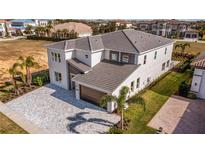 A modern two-story home featuring a gray tiled roof, brick accents, and a paved driveway and walkway at 1005 Coyote Creek Way, Reunion, FL 34747