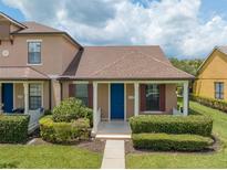 Charming townhome featuring a blue front door, manicured landscaping, and a cozy covered porch at 13636 Beauregard Pl, Orlando, FL 32837