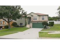 Two-story home with a green lawn, a driveway and a two-car garage, featuring stone accents and meticulous landscaping at 2750 Eagle Lake Dr, Clermont, FL 34711