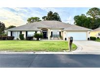 Charming single-story home featuring a manicured lawn, neutral exterior, and attached two-car garage at 3 Sunrise Dr, Ocala, FL 34472