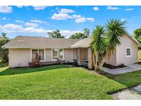 Charming single-story home with lush green lawn and mature palm trees in a sunny setting at 3 Trophy Ln, Kissimmee, FL 34759