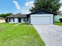 Charming single-story home featuring an attached two-car garage and a well-manicured front lawn at 406 Long Dr, Kissimmee, FL 34759