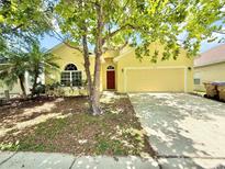 Charming yellow home with a well-manicured front yard and a two-car garage at 4307 Creeks Run Blvd, Kissimmee, FL 34746