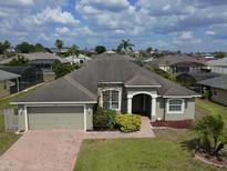 Charming single-story home with a well-manicured lawn, brick driveway, and lush landscaping at 458 Moscato Dr, Davenport, FL 33897
