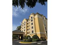 Hotel exterior featuring a covered entrance, manicured landscaping, and architectural details at 7601 Canada Ave, Orlando, FL 32819