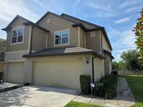 Two-story tan home featuring a two-car garage and well-maintained landscaping at 1069 Pavia Dr, Apopka, FL 32703