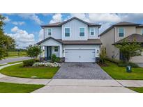 Charming two-story home with manicured lawn, flower beds, and a brick paver driveway at 1335 Greenfield Loop, Kissimmee, FL 34747