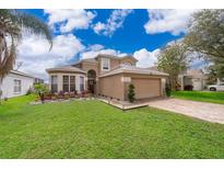 Charming two-story home with a well-manicured lawn, paver driveway and colorful garden at 13525 Mallard Cove Blvd, Orlando, FL 32837