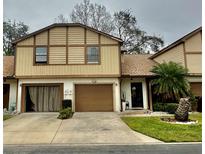 Two-story tan home with brown trim, attached garage, and well-manicured front lawn at 2031 Balboa Way, Kissimmee, FL 34741