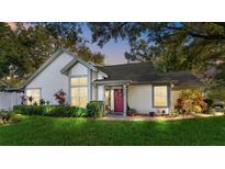 Charming home with lush landscaping, a red door, and large windows creating a welcoming curb appeal at 2225 Maryday Ct, Orlando, FL 32812