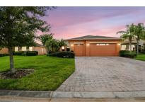 Charming single-story home featuring a paver driveway, lush landscaping, and a two-car garage at 271 Indian Wells Ave, Poinciana, FL 34759