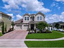 Charming two-story home with a well-manicured lawn, brick driveway, and a welcoming front porch at 2939 Sera Bella Way, Kissimmee, FL 34744