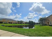 Scenic view of community pond reflecting townhouses against a blue sky with puffy clouds at 3162 Rodrick Cir, Orlando, FL 32824