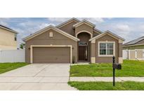 Charming single-Gathering home featuring a two-car garage, well-maintained lawn, and inviting front entrance at 326 Highland Meadows Ave, Davenport, FL 33837