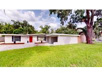 Charming single-story home with a red door and a well-manicured lawn under a blue sky at 3621 Devonswood Dr, Orlando, FL 32806