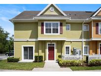 Charming two-story townhouse featuring a red front door, red shutters, and well-maintained landscaping at 4014 Santa Maria Dr # 101, Kissimmee, FL 34741