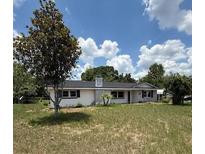 Charming single-story home features a stone chimney, mature trees, and a well-manicured lawn at 5249 Se 106Th Ln, Belleview, FL 34420