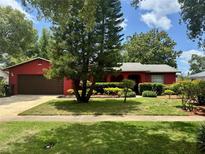 Charming single-story home with a well-maintained lawn, beautiful landscaping, and a driveway leading to the garage at 6478 Inca St, Orlando, FL 32807