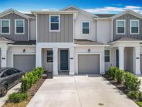 Charming townhome featuring a gray two-car garage, complemented by well-maintained landscaping at 7685 Stone Creek Trl, Kissimmee, FL 34747