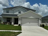 Two-story home featuring a two-car garage, well-maintained lawn, and manicured landscaping at 1016 Cascade Dr, Davenport, FL 33837