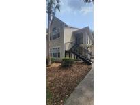 Tan two-story exterior with stairway, complemented by a mature palm tree and ground cover at 1023 S Hiawassee Rd # 4017, Orlando, FL 32835