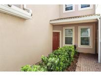 Exterior entrance showcasing well-maintained landscaping, a covered porch, and brick walkway at 1225 Bella Cara Ct # 1, Davenport, FL 33896
