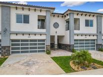 Modern townhouses featuring a two-car garage, balcony, and decorative stone accents at 1870 Brentwood Ct, Davenport, FL 33837