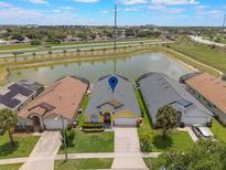 Aerial view of a lakeside home with a well-manicured lawn and a community in the background at 2685 Oneida Loop, Kissimmee, FL 34747