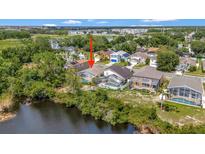 Aerial view of a home with a screened pool overlooking a pond surrounded by lush greenery at 307 Balmoral Ct, Davenport, FL 33896