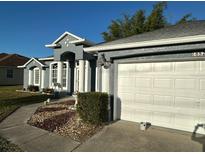 Charming single-story home featuring a gray exterior, white trim, arched windows, and a two-car garage at 852 Adour Dr, Kissimmee, FL 34759