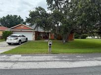 Charming one-story home with a large tree in front and a well-maintained lawn and a white SUV in the driveway at 925 Derbyshire Dr, Kissimmee, FL 34758